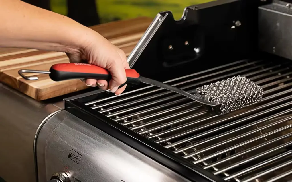 Professional cleaner using steam and degreaser on a stainless‑steel barbecue