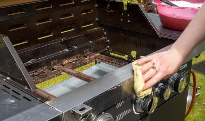 Grill specialist replacing burners and ignition components on a backyard BBQ