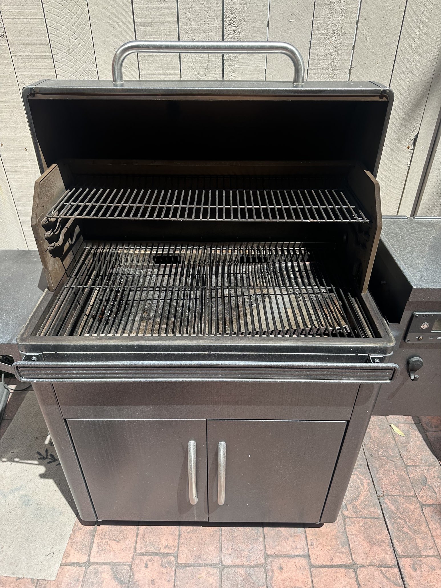 Interior of a built‑in BBQ grill coated with grease and rust prior to professional cleaning